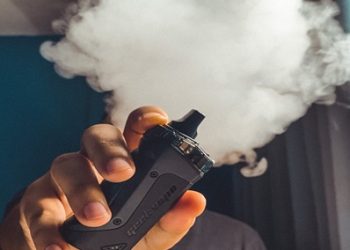 A man vaping, smoke is forming.